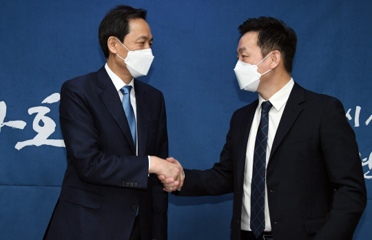 우상호 민주당 의원과 정봉주 열린민주당 예비후보가 7일 국회 의원회관에서 만나 범여권 서울시장 후보 단일화 합의를 발표하고 악수하고 있다. 연합뉴스